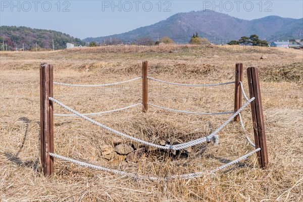 Water well cordoned off with wooden beams and rope at remains of stone fortress in Yeosu, South