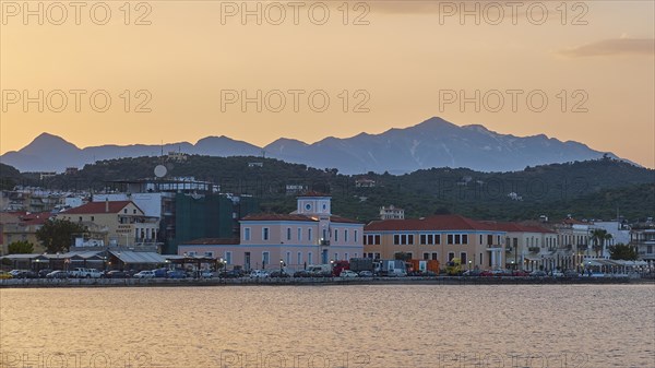 Coastline with buildings and mountains during a colourful sunset, Snow-covered Taygetos Mountains,