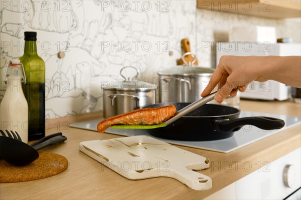 Closeup view of female hand holding fried trout steak on a spatula over the serving board in the