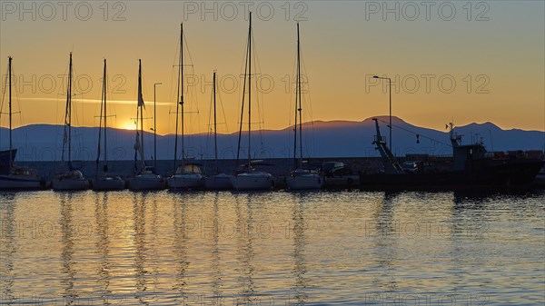 Yachts in the harbour at sunset with mountains in the background and evening sky, Gythio, Mani,