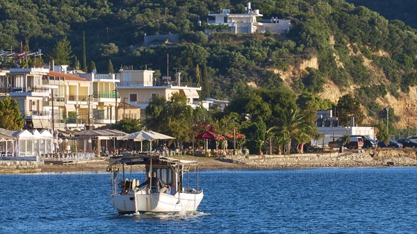 Fishing boat on an idyllic Mediterranean coast with town and hills in the background, Gythio, Mani,