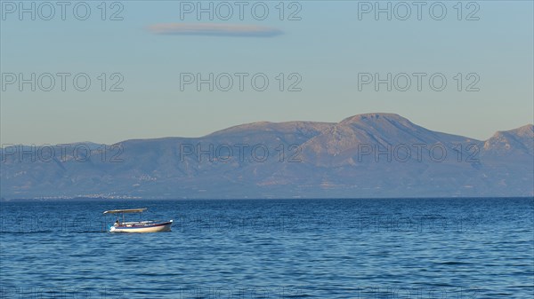 Lonely boat on the wide blue sea with mountains in the background and clear sky, Gythio, Mani,