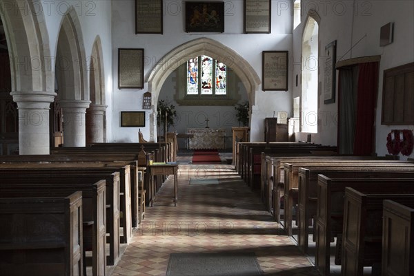 View past wooden pews to chancel arch and altar in sanctuary in the church at Milton Lilbourne,