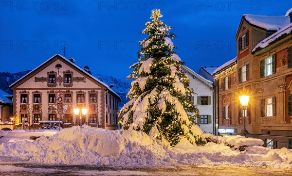Snow-covered Christmas tree on the historic Ludwigstrasse in the Partenkirchen district at dusk,
