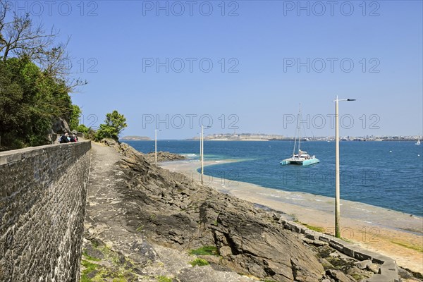 Fortified coast with catamaran in front of rocky shore in Dinard, Ille-et-Vilaine, Brittany,