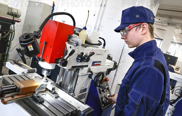A trainee mechatronics technician works with a bench drill on a workpiece in a Deutsche Bahn