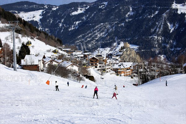 Ladis in winter, the ski piste in the foreground and the village with Laudegg Castle in the