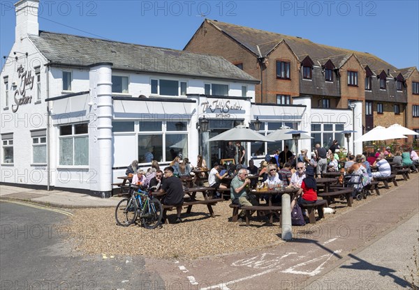 People sitting in sunshine outside the Jolly Sailors pub, Pakefield, Lowestoft, Suffolk, England,