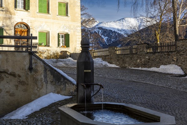 Wooden fountain, house with sgraffito, facade decorations, mountain peak, snow, winter, Guarda,