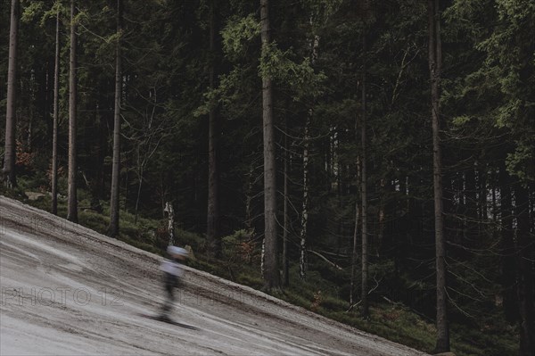 A skier skis on an artificially snow-covered and dirty slope, taken on a ski slope in the Jizera