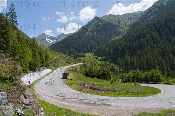 Camper on a winding mountain road, surrounded by forest and snow, mountain road, Transfogarasan