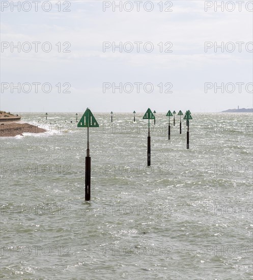 Green triangular warning markers on posts in shallow water at River Orwell river mouth, Landguard