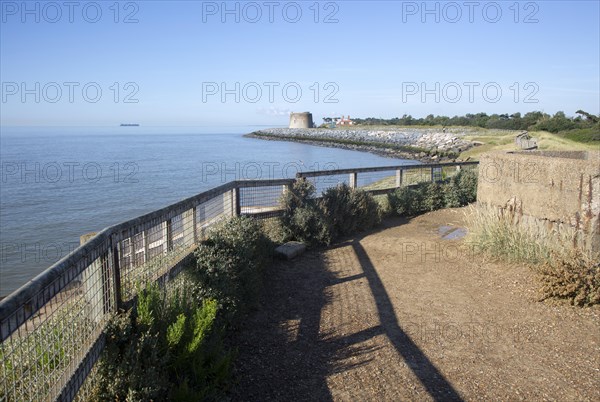 Martello tower defended by rock armour coastal defences at Bawdsey, Suffolk, England, UK calm sea