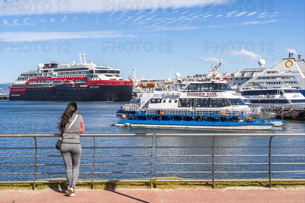 A woman watches cruise ships in the harbour on the Beagle Channel, Ushuaia, Tierra del Fuego