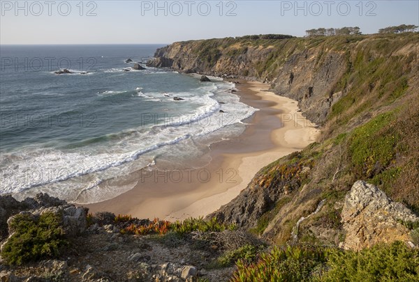 Secluded sandy beach in bay between rocky headlands at Parque Natural do Sudoeste Alentejano e
