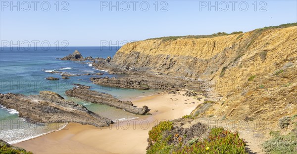 Sandy beach Praia dos Alteirinhos, Zambujeira do Mar in bay between rocky headlands part of Parque