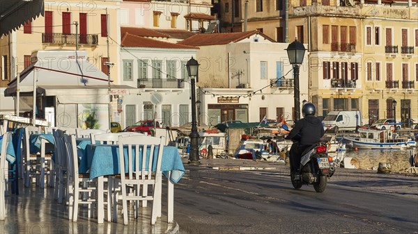 A scooter rides early in the morning at a cafe along the coastal road overlooking the sea, Gythio,
