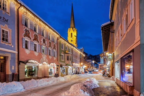 Snow-covered historic Ludwigstrasse in the Partenkirchen district with Christmas lights at dusk,