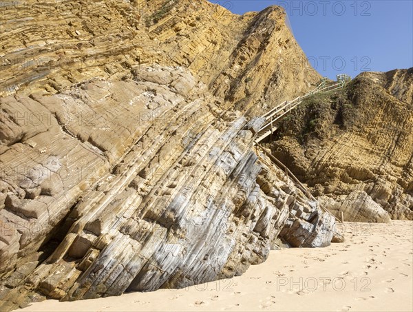 Folded sedimentary rock strata dipping downwards in cliff at Praia dos Alteirinhos, Zambujeira do