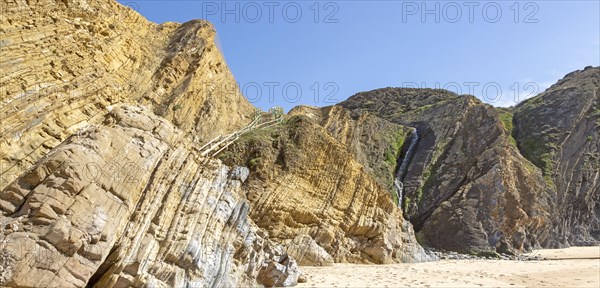 Folded sedimentary rock strata dipping downwards in cliff at Praia dos Alteirinhos, Zambujeira do