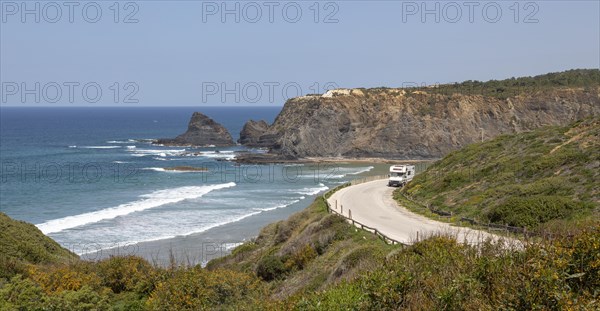 Motorhome parked at viewpoint of Atlantic Ocean waves breaking on rocky headland and bay with sandy