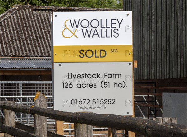 Estate agent Woolley and Wallis property sold sign at livestock farm near Potterne, Wiltshire,
