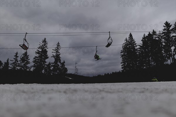 Skiers ride a chairlift, taken on a ski slope in the Jizera Mountains ski area near Albrechtice v