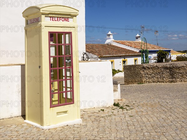Old fashioned Telephone Telefone box kiosk in street of traditional Portuguese village, Cacela