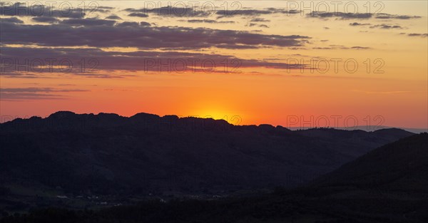 Sunset with glowing sky orange sun dropping behind hills. Photo taken looking south west from