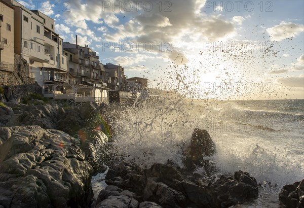 Sea water crashes against the cliffs of the rugged coastline in the town of Cefalu, Sicily, Italy,