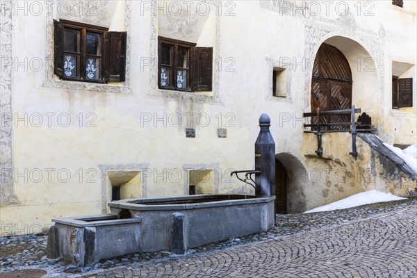 Wooden fountain in front of a historic house, sgraffito, facade decorations, Guarda, Engadin,