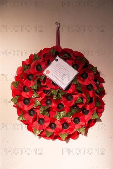 'We will remember them' remembrance day poppy wreath hanging from wall inside the church at South