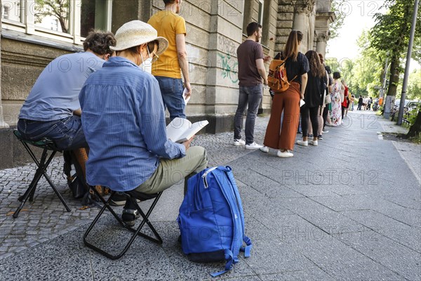 Vaccinated people in a queue sitting on folding chairs. Neighbourhood residents in the Tempelhof