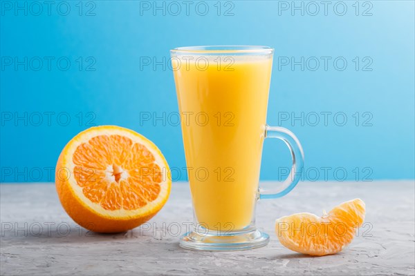 Glass of orange juice on a gray and blue background. Morninig, spring, healthy drink concept. Side