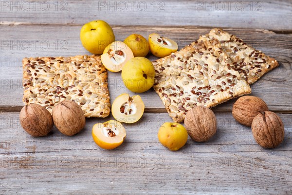 Biscuits with flax, sesame and sunflower seeds and yellow quince fruit on a rustic wooden