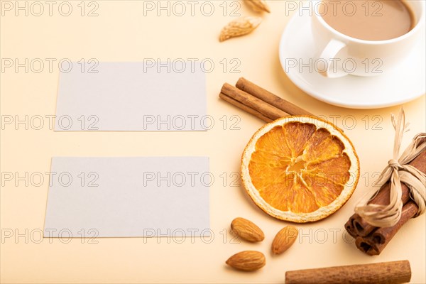 Composition of gray paper business cards, almonds, cinnamon and cup of coffee. mockup on orange