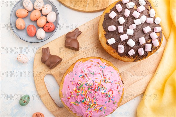 Homemade glazed and decorated easter pies with chocolate eggs and rabbits on a white concrete
