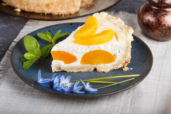 A piece of peach cheesecake on a blue ceramic plate with blue flowers and a cup of coffee on a