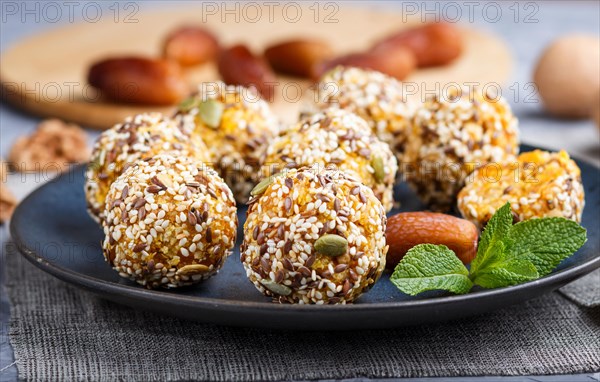 Energy ball cakes with dried apricots, sesame, linen, walnuts and dates with green mint leaves on a