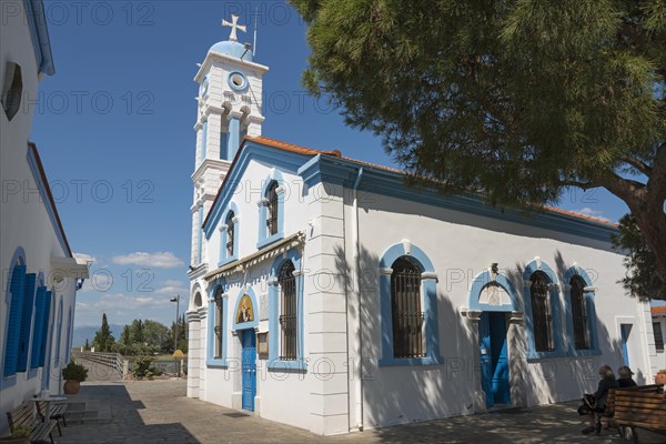 Church on a sunny day, people sitting on park benches in the shade, Monastery of St Nicholas,