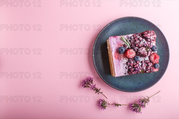Berry cake with milk cream and blueberry jam on blue ceramic plate on a pink pastel background. top