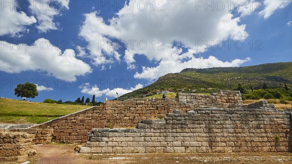 Ruins of an ancient wall in front of a light blue sky with fleecy clouds, Archaeological site,