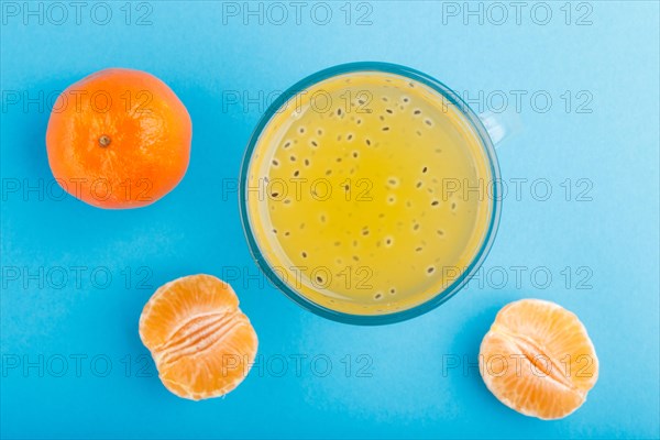 Glass of tangerine orange colored drink with basil seeds on a blue background. Morninig, spring,