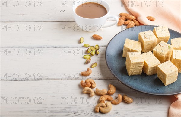 Traditional indian candy soan papdi in a blue ceramic plate with almond, pistache, cashew and a cup