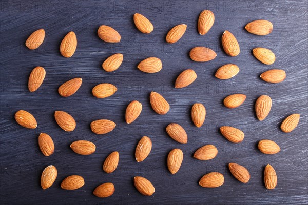 Pattern and texture made from almonds on black wooden background, flat lay. top view