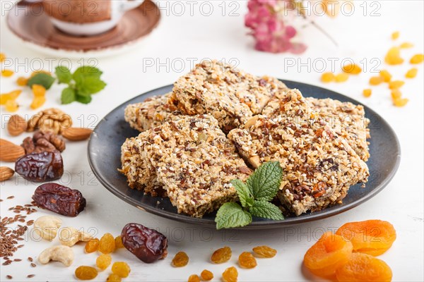 Homemade granola from oat flakes, dates, dried apricots, raisins, nuts in blue ceramic plate with a