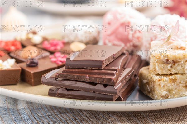A pieces of homemade chocolate with coconut candies on a blue and brown textile. side view, close