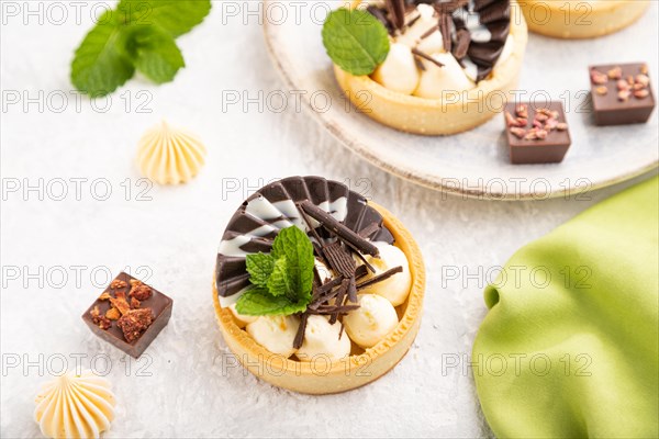 Sweet tartlets with chocolate and cheese cream with cup of coffee on a gray concrete background and