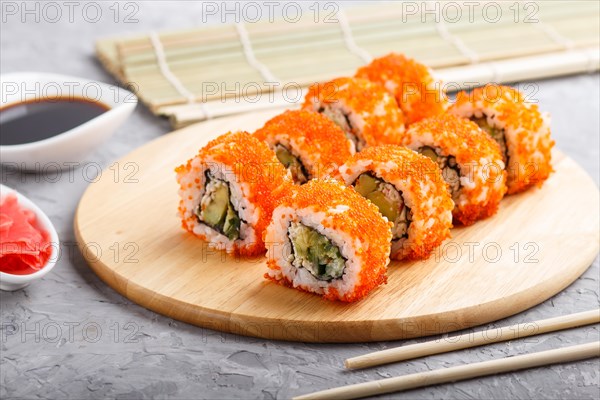 Japanese maki sushi rolls with flying fish roe, chopsticks, soy sauce and marinated ginger on