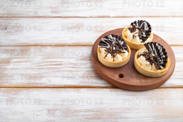 Sweet tartlets with chocolate and cheese cream on a white wooden background. side view, close up,